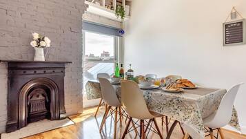 A dining area with a table set for breakfast, a fireplace, and a view through a window.