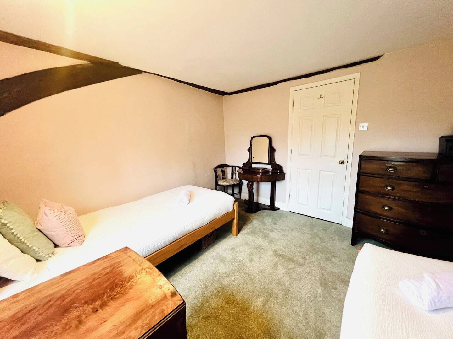 Ein Schlafzimmer mit einem Einzelbett, einem Nachttisch aus Holz, einem Schrank, einem Stuhl und einem Schreibtisch mit Spiegel.