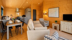 Et hyggeligt sommerhusinteriør med spiseområde, sofa, fjernsyn og et kort på væggen.