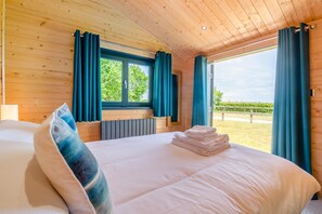 A wooden-paneled room with a bed, a window with curtains, and a view of a vineyard. - 2 Bed in Nafferton (oc-o31954) (Nafferton)