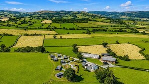 A rural landscape with fields, a small cluster of buildings, and distant hills. - 2 Bed in Llandinam (oc-t31972) (Llandinam)