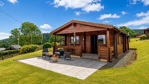 A wooden cabin with a patio, outdoor seating, and a view of the surrounding landscape. - 2 Bed in Llandinam (oc-t31974) (Llandinam)