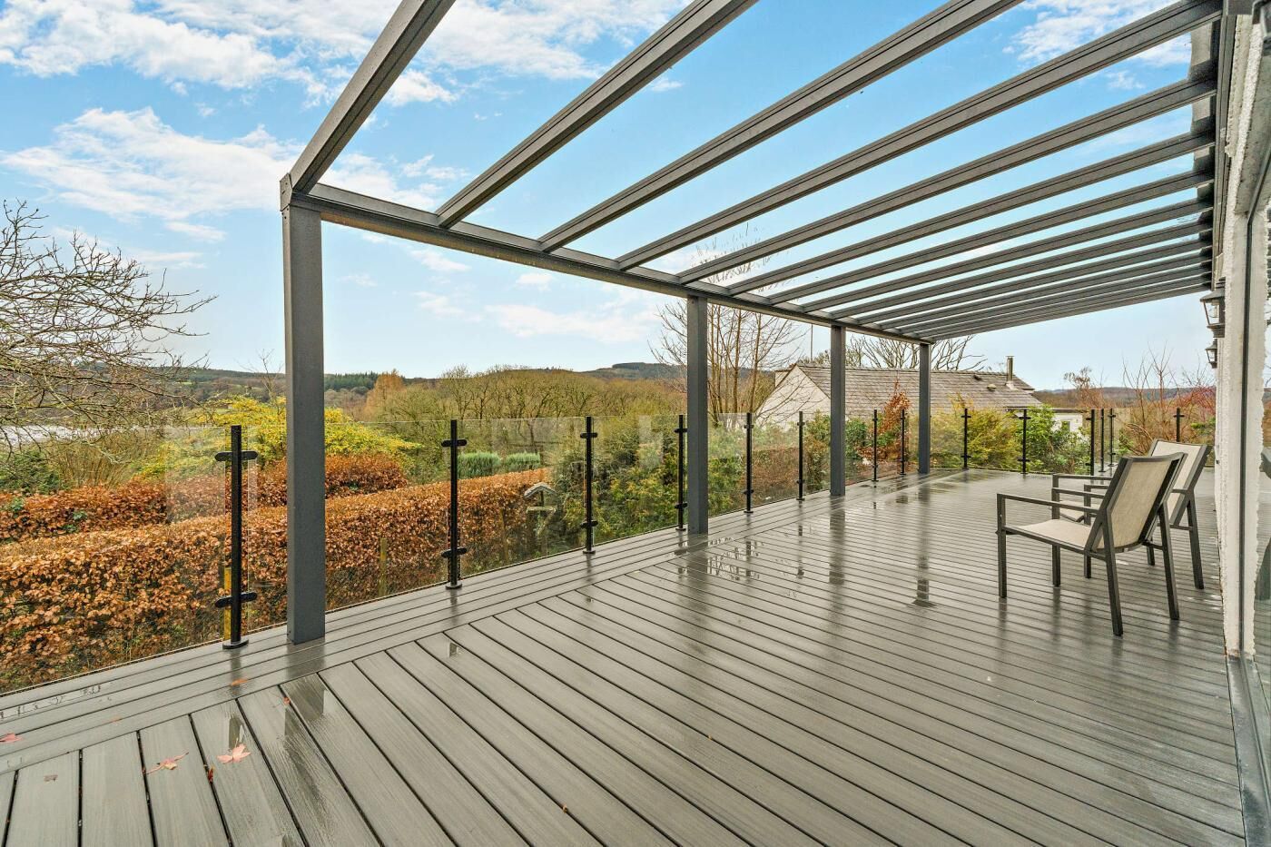 Una terraza techada al aire libre con vista a un jardín ajardinado y edificios distantes.