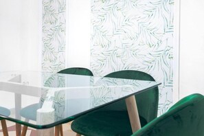 A glass-top table with chairs, a patterned wallpaper, and a window. - Stay near Feria, Madrid (Seville)