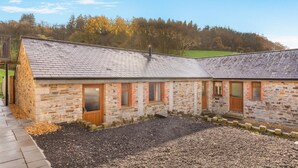 A stone building with a sloped roof, multiple windows, and a gravel driveway. - 2 Bed in Bodmin (oc-m32909) (Saint Winnow)