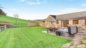 A house with a stone exterior, a patio with outdoor furniture, and a well-maintained lawn. - 2 Bed in Bodmin (oc-m32909) (Saint Winnow)