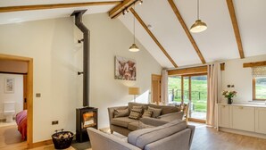 A cozy living room with a fireplace, a sofa, and a view of the outdoors. - 2 Bed in Bodmin (oc-m32909) (Saint Winnow)