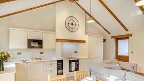 A modern kitchen with white cabinetry, a wooden ceiling, and a dining area with a table set for two. - 2 Bed in Bodmin (oc-m32909) (Saint Winnow)