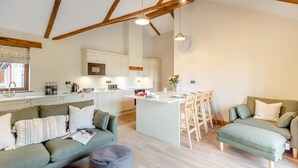 Een moderne keuken met witte kasten, een centraal eiland en houten balken in het plafond.