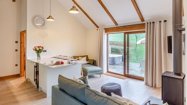 Een moderne keuken met een centraal eiland, een zithoek met een bank, en een schuifdeur naar een bubbelbad buiten.