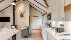 Een moderne keuken met een ingebouwde kookplaat, witte kasten en een houten plafond.