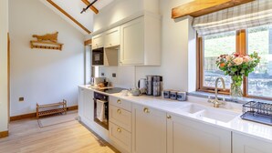 A modern kitchen with white cabinets, a built-in oven, a microwave, and a window with a view of the outdoors. - 2 Bed in Bodmin (oc-w32907) (Saint Winnow)