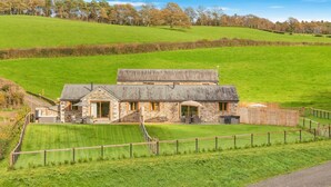 A stone house with a fenced yard, a patio, and a view of the surrounding countryside. - 2 Bed in Bodmin (oc-w32907) (Saint Winnow)