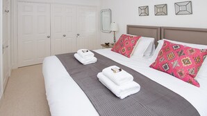 A hotel room with a large bed, two white towels, a grey bedspread, a brown headboard, and three decorative mirrors on the wall. - 2 Bed in Bath (oc-bhr50) (Bath)