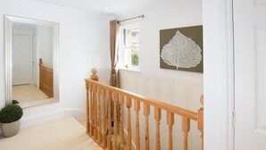 A hallway with a wooden staircase, a large mirror, a potted plant, and a wall-mounted artwork. - 2 Bed in Bath (oc-bhr50) (Bath)