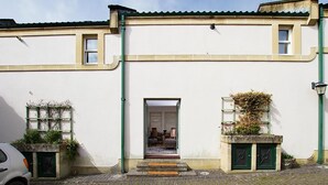 A building with a white facade, a green door, and a visible entrance leading to an interior with furniture. - 2 Bed in Bath (oc-bhr50) (Bath)