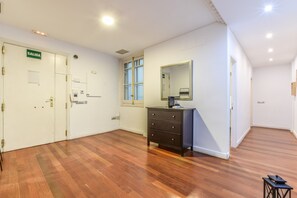 Ein Zimmer mit Holzboden, einem Schminktisch, einem Spiegel und einer Tür mit der Aufschrift 'SALIDA'.