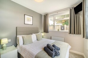 A bedroom with a bed, two bedside tables, a window with curtains, and a radiator. - 4 Bed in Bath (oc-bhr4) (Bath)