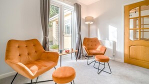 A room with two orange armchairs, a small table, a floor lamp, and a wooden door. - 4 Bed in Bath (oc-bhr4) (Bath)
