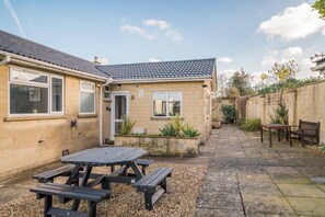 A residential property with a tiled roof, a patio with a table and benches, and a garden area with plants. - 4 Bed in Bath (oc-bhr4) (Bath)