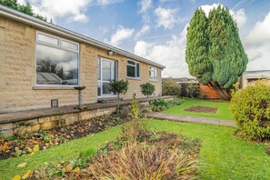 A residential building with a stone facade, large windows, and a well-maintained garden with a tall coniferous tree. - 4 Bed in Bath (oc-bhr4) (Bath)