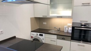 A modern kitchen with a built-in washing machine, a coffee maker, and an oven.