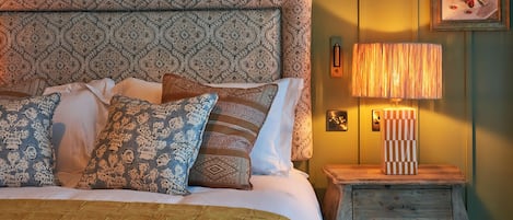 A bed with patterned pillows, a bedside lamp, and a wooden nightstand with a drawer.