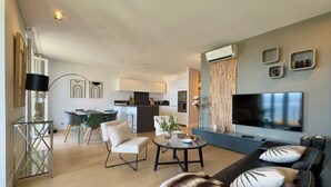 Una sala de estar moderna con sofá, televisor y comedor con sillas y una mesa.