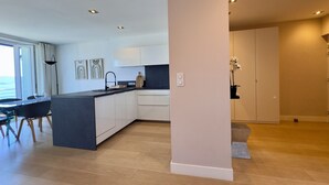 Una cocina moderna con una isla central, armarios blancos y un comedor con mesa y sillas.