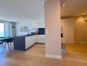 Eine moderne Küche mit Kochinsel, weißen Schränken und einem Essbereich mit Tisch und Stühlen.