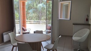 A dining area with a round table and chairs, a ceiling fan, and a view of the outdoors.