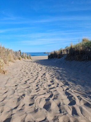 A sandy beach path with a wooden fence on one side and a clear blue sky above. - Evasion Marine, an air-conditioned house near the beach (Marseillan)