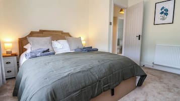A neatly made bed with a grey duvet, a wooden headboard, and a bedside lamp.