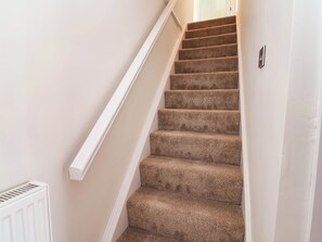 A carpeted staircase with white handrails and a white radiator on the left. - Araelfa (Llangollen)