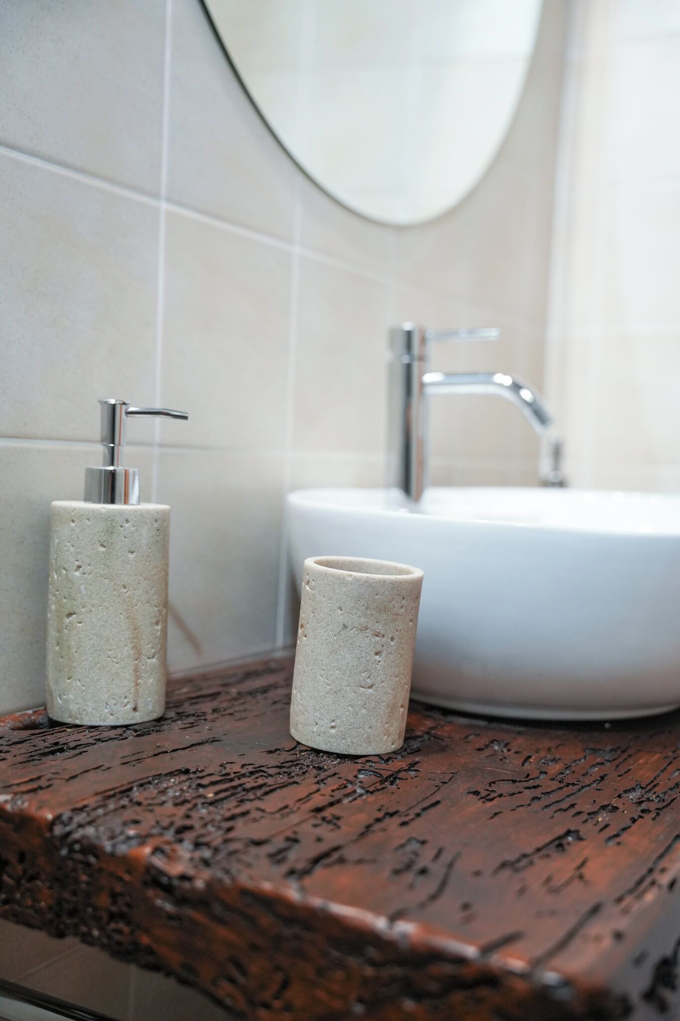 A bathroom with a white sink, a mirror, and two cylindrical containers on a wooden countertop.