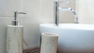 A bathroom with a white sink, a mirror, and two cylindrical containers on a wooden countertop.