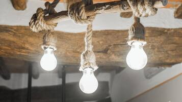 A rustic ceiling with exposed beams and a rope light fixture with two bulbs.