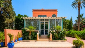 Een gebouw met een glazen ingang, een overdekte veranda en potplanten.