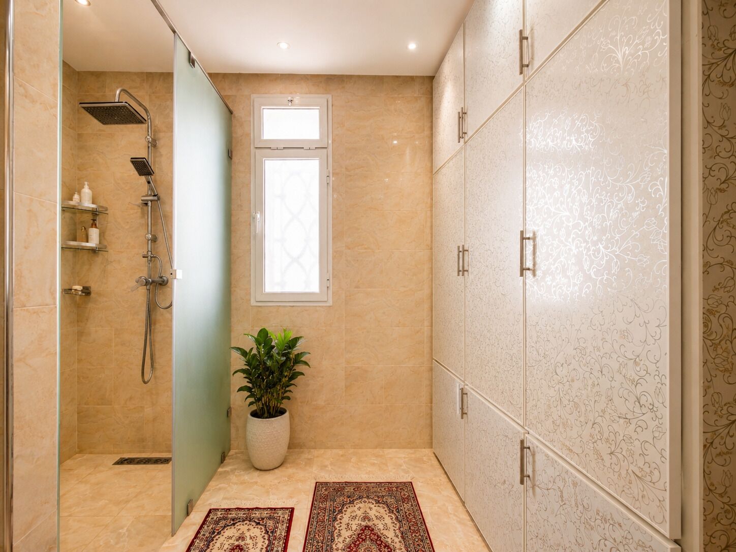 A bathroom with a shower, a potted plant, a window, and a patterned wall.