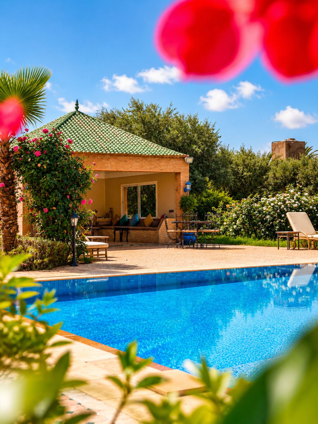 Zona junto a la piscina con piscina, sillas de descanso y un edificio con tejado de baldosas.