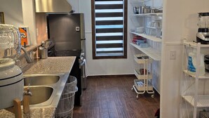 Cozinha com frigorífico de aço inoxidável, forno embutido, uma pia dupla e chão de madeira.