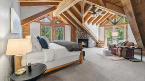 Une chambre confortable aménagée en mezzanine, avec un lit, une cheminée, un canapé et une table à manger.