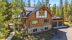 Une cabane en rondins avec des fondations en pierre, de grandes fenêtres et un garage.