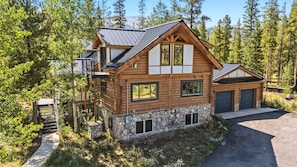 A log cabin with a stone foundation, large windows, and a garage. - Breckenridge Outdoor Oasis | Pool Table + Hot Tub (Breckenridge)
