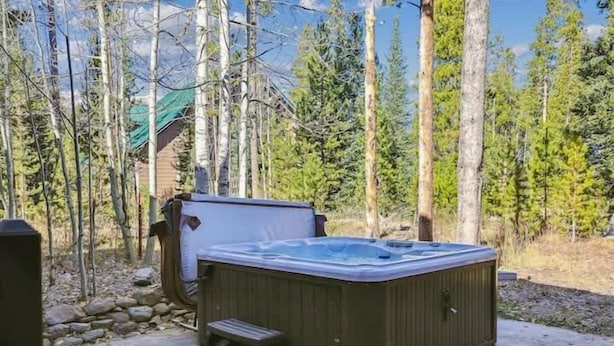 Un bain à remous situé dans un espace boisé, avec une terrasse en bois et des marches menant à celui-ci.
