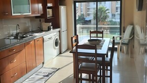 Una cucina moderna con mobili in legno, un forno a microonde integrato e un'area pranzo con tavolo e sedie.