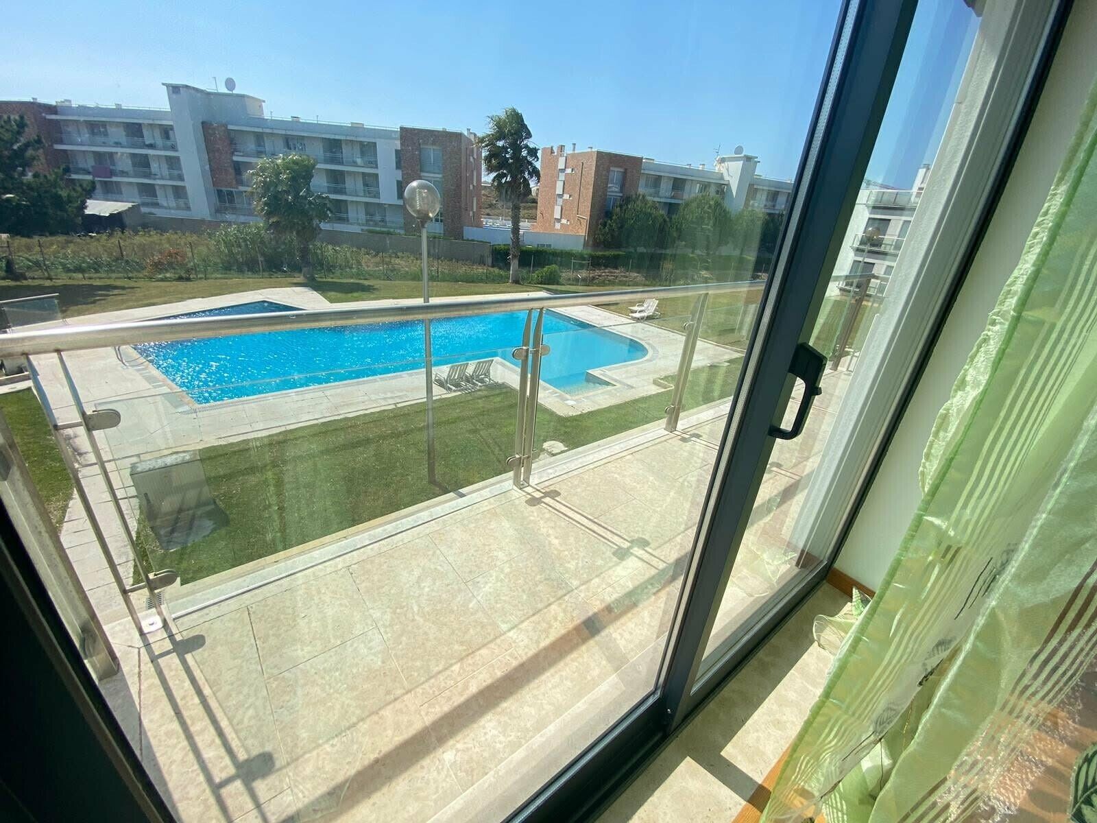 Ein Wohngebäude mit Swimmingpool, einem Glasbalkon und Blick auf andere Gebäude.