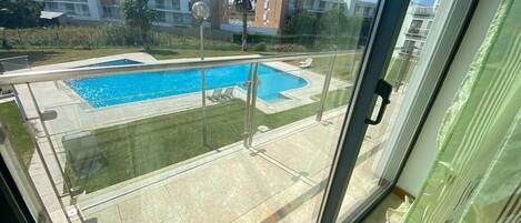 Ein Wohngebäude mit Swimmingpool, einem Glasbalkon und Blick auf andere Gebäude.