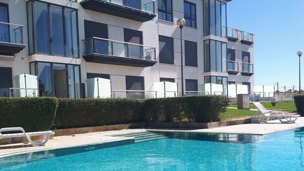 Un edificio moderno con piscina, caratterizzato da balconi e ampie finestre.
