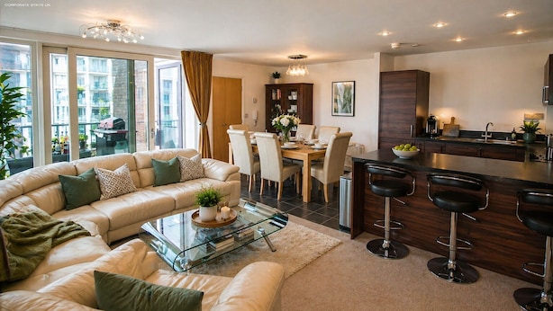 Een moderne woonkamer met een bank, eettafel en keukenhoek.
